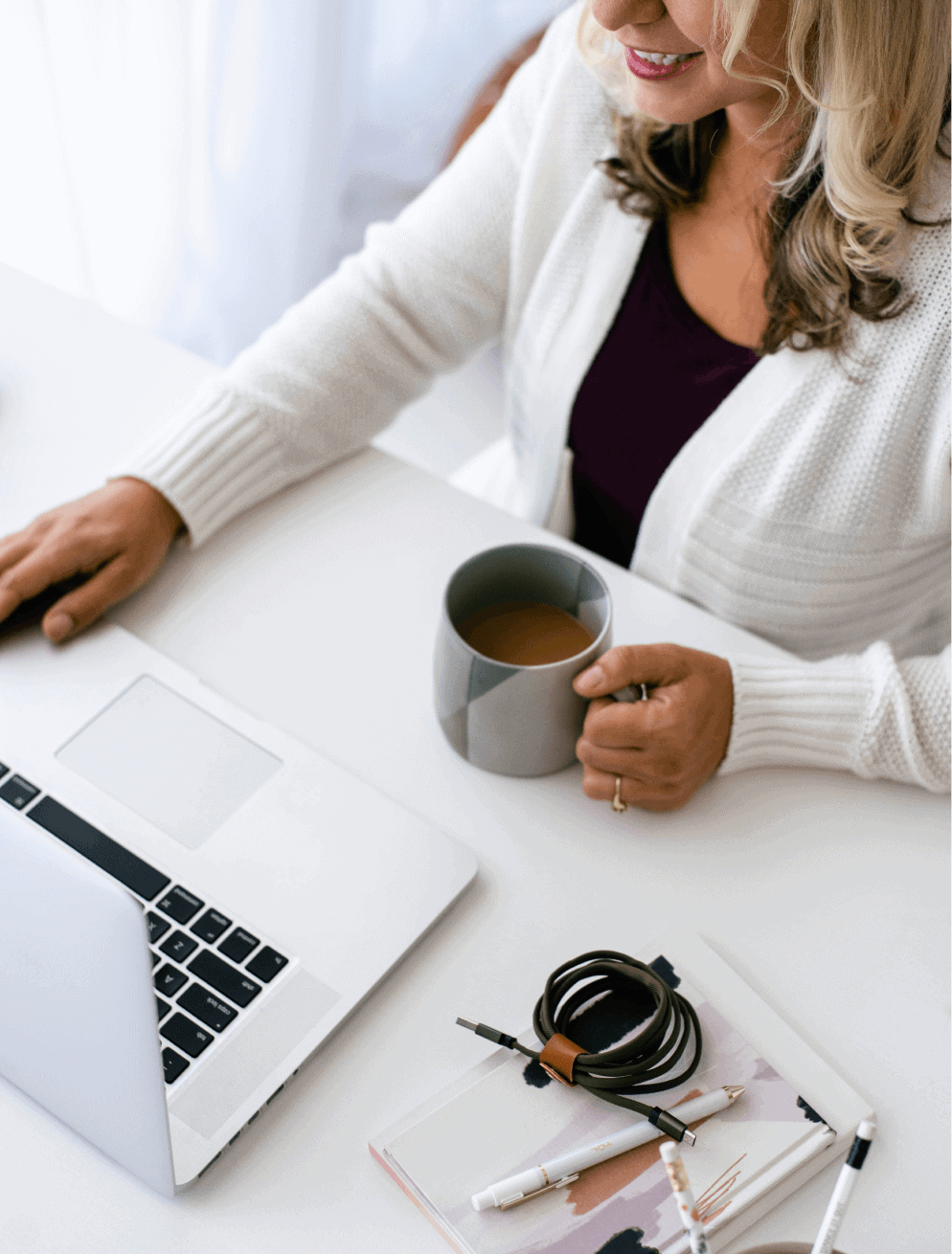 women sitting at desk with laptop and coffee